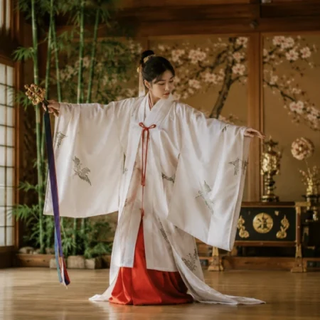 Hitaar practitioner in traditional Japanese ceremonial kimono performing a slow ritual movement inside a wooden hall with shoji screen lighting