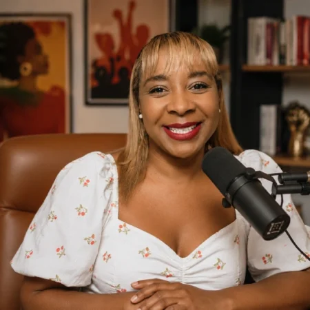 Sabrina Salvati sitting at a podcast microphone in her studio — known for the Sabby Sabs podcast