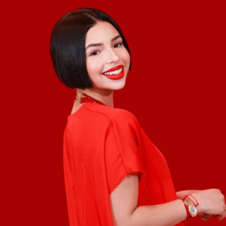 Ángela Aguilar smiling in a red dress — photo related to Ángela Aguilar net worth article