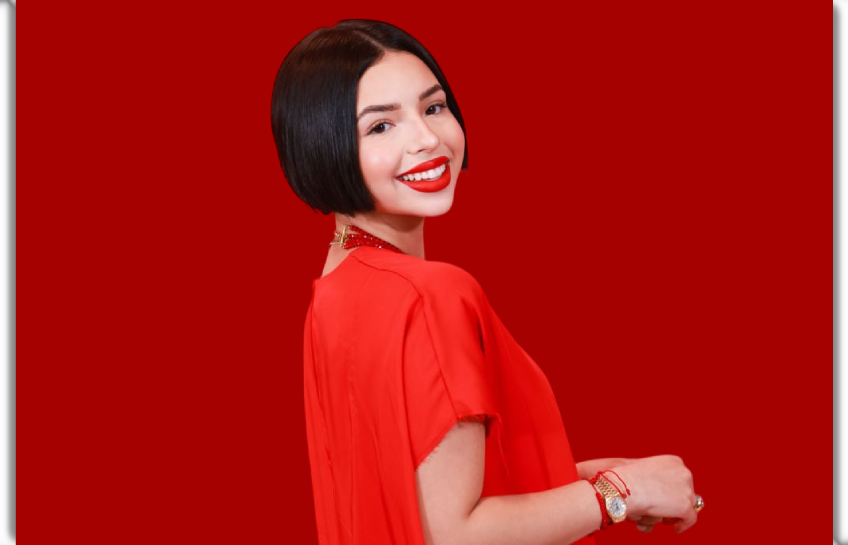 Ángela Aguilar smiling in a red dress — photo related to Ángela Aguilar net worth article