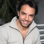 Eugenio Derbez smiling in a grey zip-up jacket at a media event, Mexican actor and producer known for Instructions Not Included and CODA