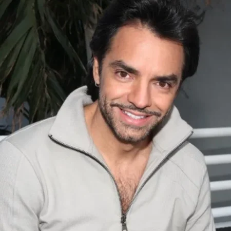 Eugenio Derbez smiling in a grey zip-up jacket at a media event, Mexican actor and producer known for Instructions Not Included and CODA