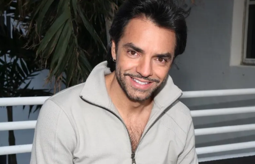 Eugenio Derbez smiling in a grey zip-up jacket at a media event, Mexican actor and producer known for Instructions Not Included and CODA