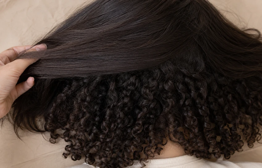 Woman's hair showing irish curls pattern with straight canopy on top and curly layers underneath