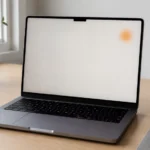 MacBook display showing a small orange spot on the screen while placed on a desk.