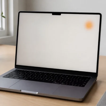 MacBook display showing a small orange spot on the screen while placed on a desk.